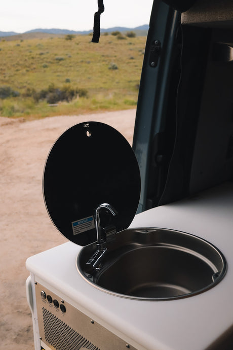 RV rental's compact sink and faucet unit, showing controls for awning/lights, ready for van life adventures.