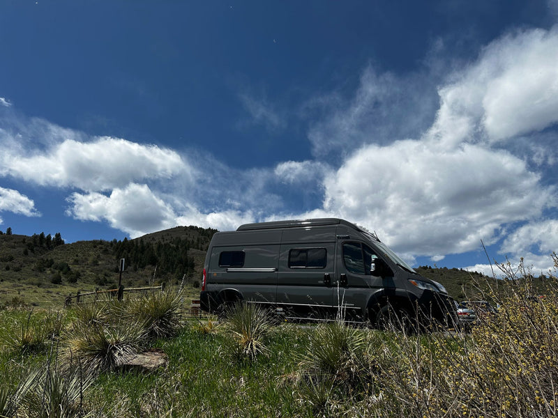  ideal for your next RV rental adventure.|Grey camper van (Winnebago Solis) parked in a scenic grassy area with hills & blue sky. Perfect for an RV rental adventure!|Your next RV rental: A modern grey camper van parked roadside on a scenic route with red rock hills and clear blue sky.|RV rental: A dark grey Winnebago Solis van parked roadside in rocky — photo 4