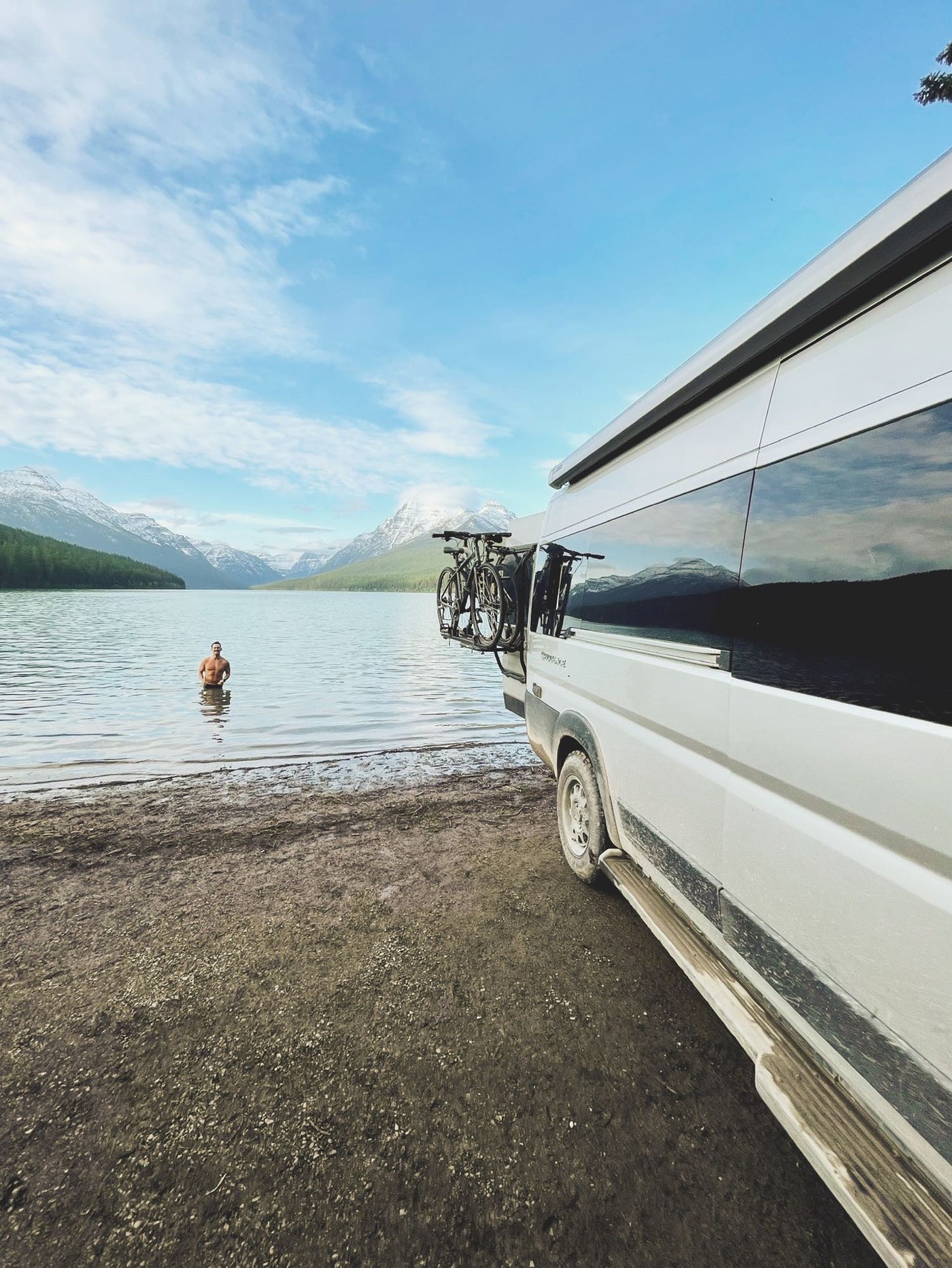  and a striped blanket facing a scenic nature view. (THOR RV visible).|Modern silver RV rental van with a pop-top roof extended — photo 4