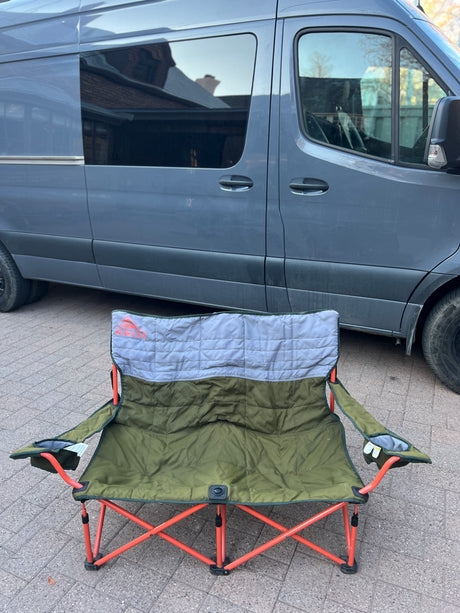 Ready for your next rv rental trip! A comfy Kelty double camping chair sits before a sleek grey camper van.