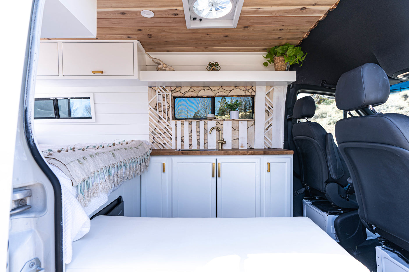 Interior of a modern camper van RV rental with a cozy bed, stylish kitchen, and natural wood accents. Perfect for travel.