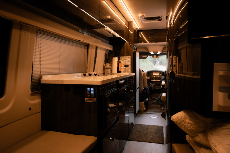 Step inside this elegant rv rental: a well-appointed kitchen, ambient lighting, and comfy living space leading to the cockpit. — photo 13