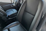 Black leather-style seats inside an RV rental van, highlighting the comfortable driver and passenger areas.