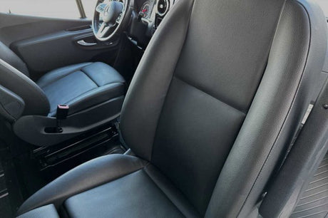 Black leather-style seats inside an RV rental van, highlighting the comfortable driver and passenger areas.