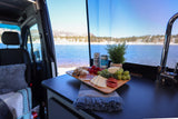 Cozy RV rental interior with a charcuterie board and stunning lake views, perfect for scenic adventures.