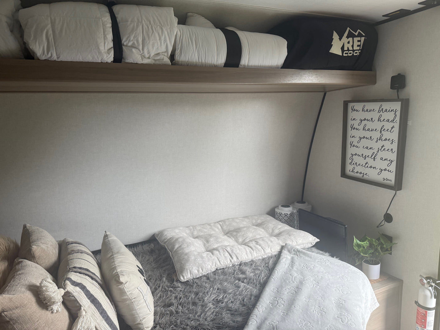 Cozy RV rental bedroom with bunk bed, soft bedding, decorative pillows, Dr. Seuss quote, and a fire extinguisher. — photo 3