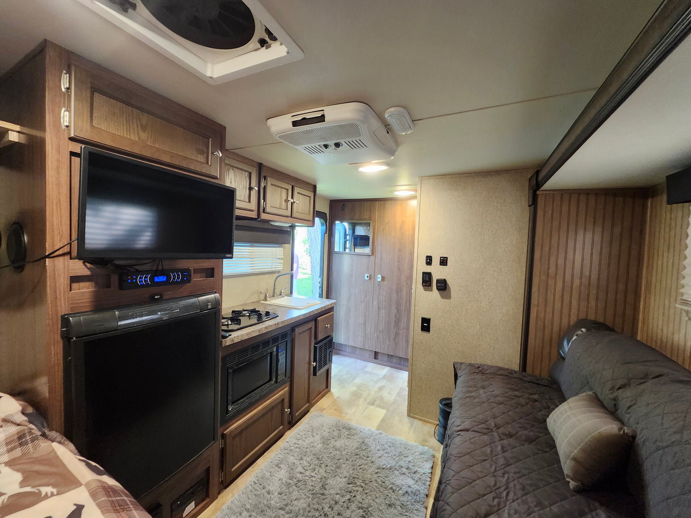 Inside this modern RV rental: a compact kitchen, entertainment area with TV, and cozy sleeping space for road trips.