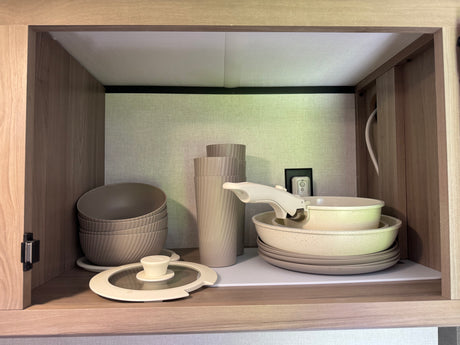 RV rental: Compact cabinet neatly storing stackable bowls, cups, pots, pans, and plates for your adventures.