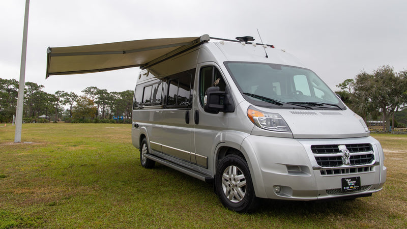  awning extended. A small bird rests on the side mirror.|Silver RV rental camper van parked in a grassy field with an extended awning. A bird is perched on its side mirror.|This RV rental's rear doors are open — photo 2