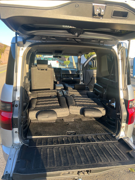 Open tailgate of a spacious vehicle with seats folded flat, ready for car camping or an rv rental.