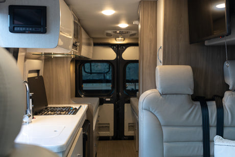 RV rental: Modern interior featuring a kitchen with stovetop, comfortable passenger seating, and TV.