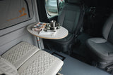 This RV rental features a compact dining area with metal tableware on an oval table, swivel front seats, and quilted bench seating.