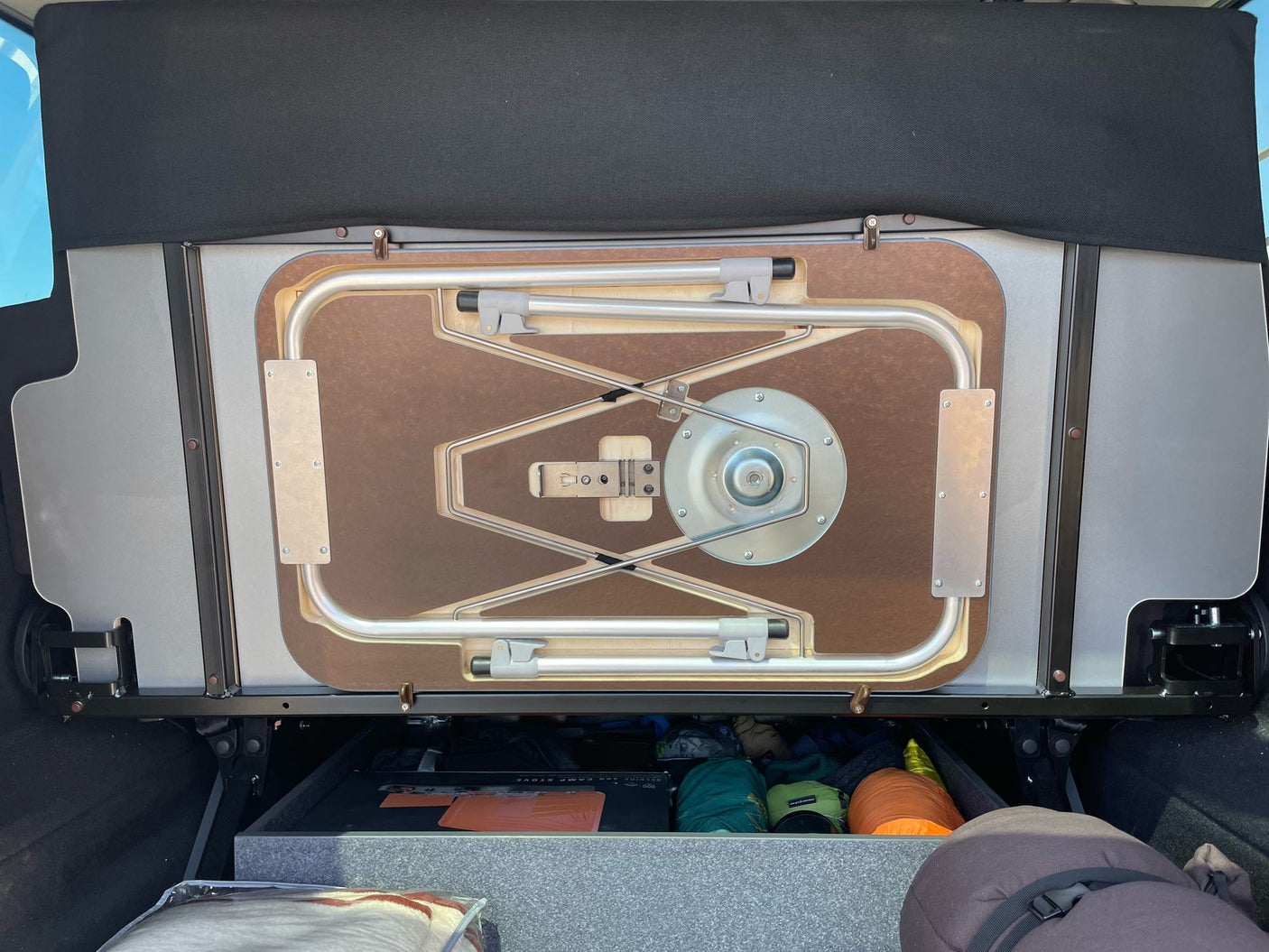 RV rental: Cargo area showing a custom stowed table and efficient storage for camping equipment below.
