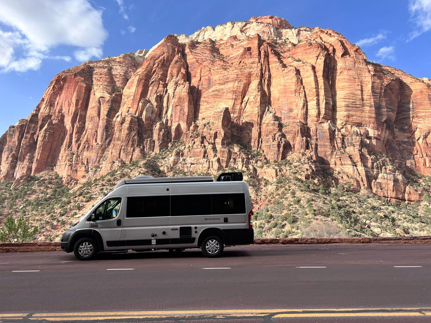 An RV rental, a grey camper van, parked beside majestic red rock cliffs. Perfect for national park adventures! — photo 3