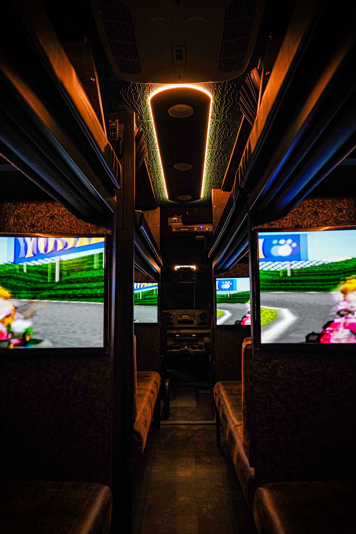 Experience mobile gaming in this custom RV rental, featuring multiple screens playing Mario Kart and plush seating inside.