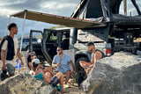 An RV rental Jeep Gladiator with rooftop tent and awning provides comfort for friends enjoying an outdoor glamping trip.