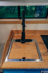 Compact RV rental kitchen featuring bamboo countertops, a covered sink with a modern faucet, and a scenic window view.
