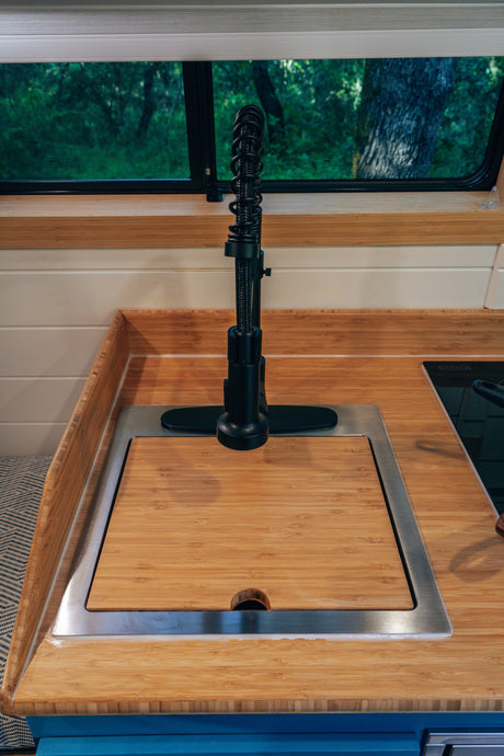 Compact RV rental kitchen featuring bamboo countertops, a covered sink with a modern faucet, and a scenic window view.
