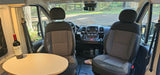 Inside an RV rental: front cabin with seats, dash, and a cozy table. Ready for a scenic road trip adventure.
