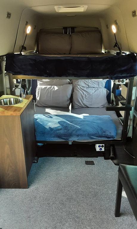 This RV rental features comfortable bunk beds and a compact kitchenette with a sink, perfect for camper travel.