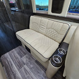 RV rental interior with cream quilted bench seating, wood floor, cup holders, and a view outside.