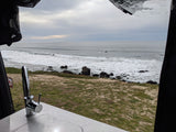 Oceanfront RV rental view: waves, rocky shore, and an interior sink, perfect for a coastal van life adventure.