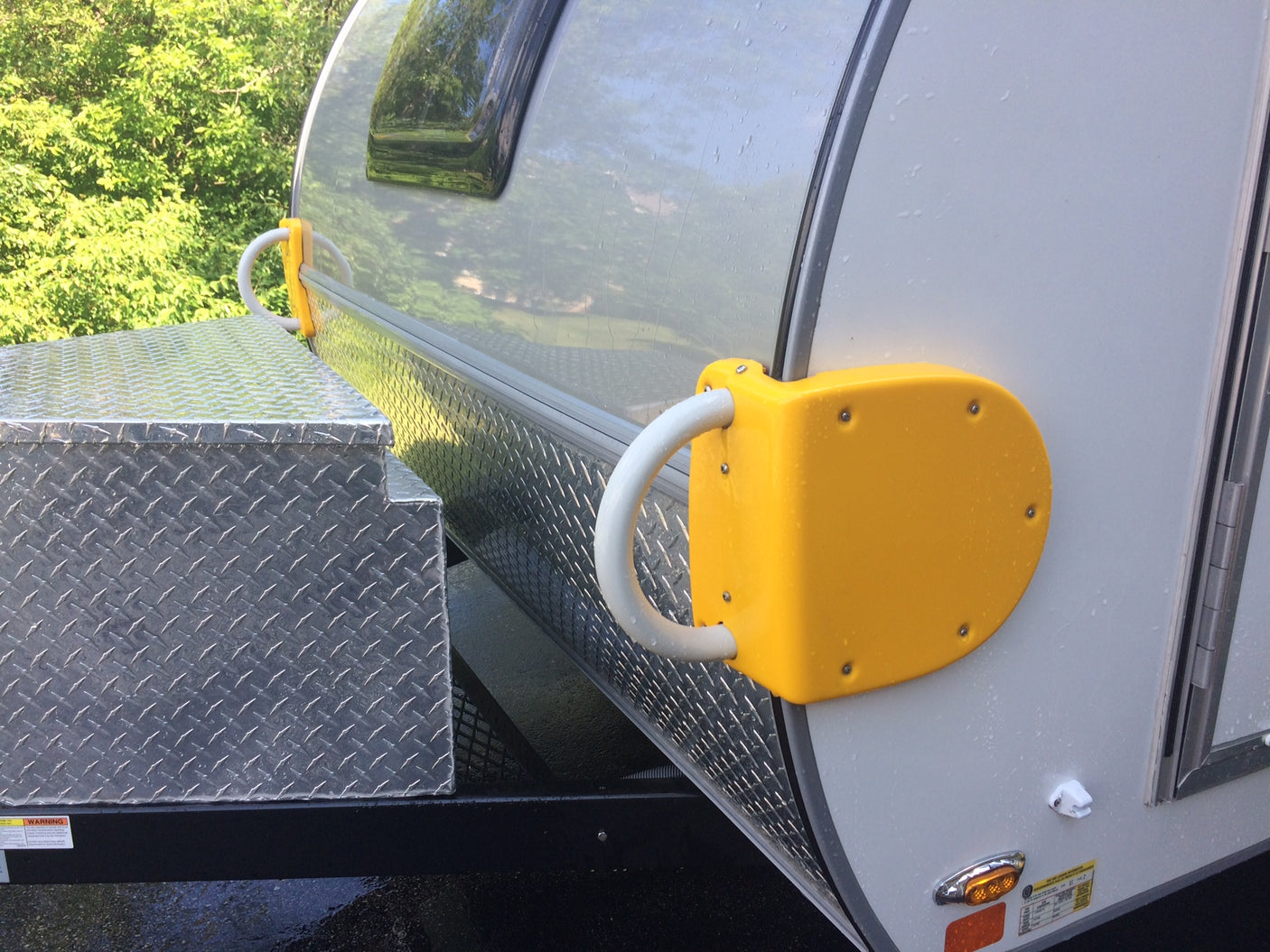 Closeup of an RV rental with a bright yellow protective bumper/grab handle and a diamond plate storage box.