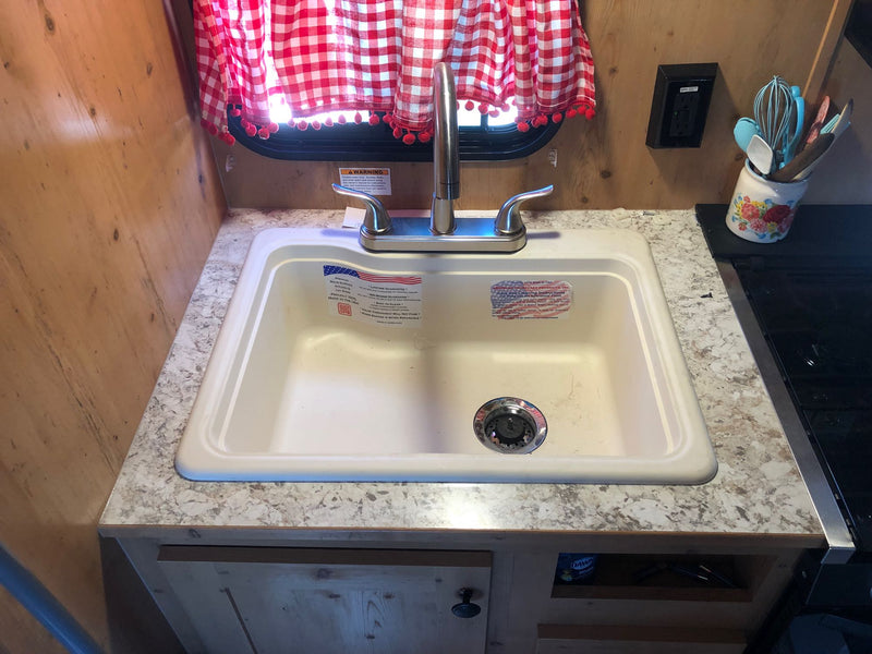 Compact RV rental kitchen with a white double sink, chrome faucet, granite-look counter, and red checkered curtains. — photo 11