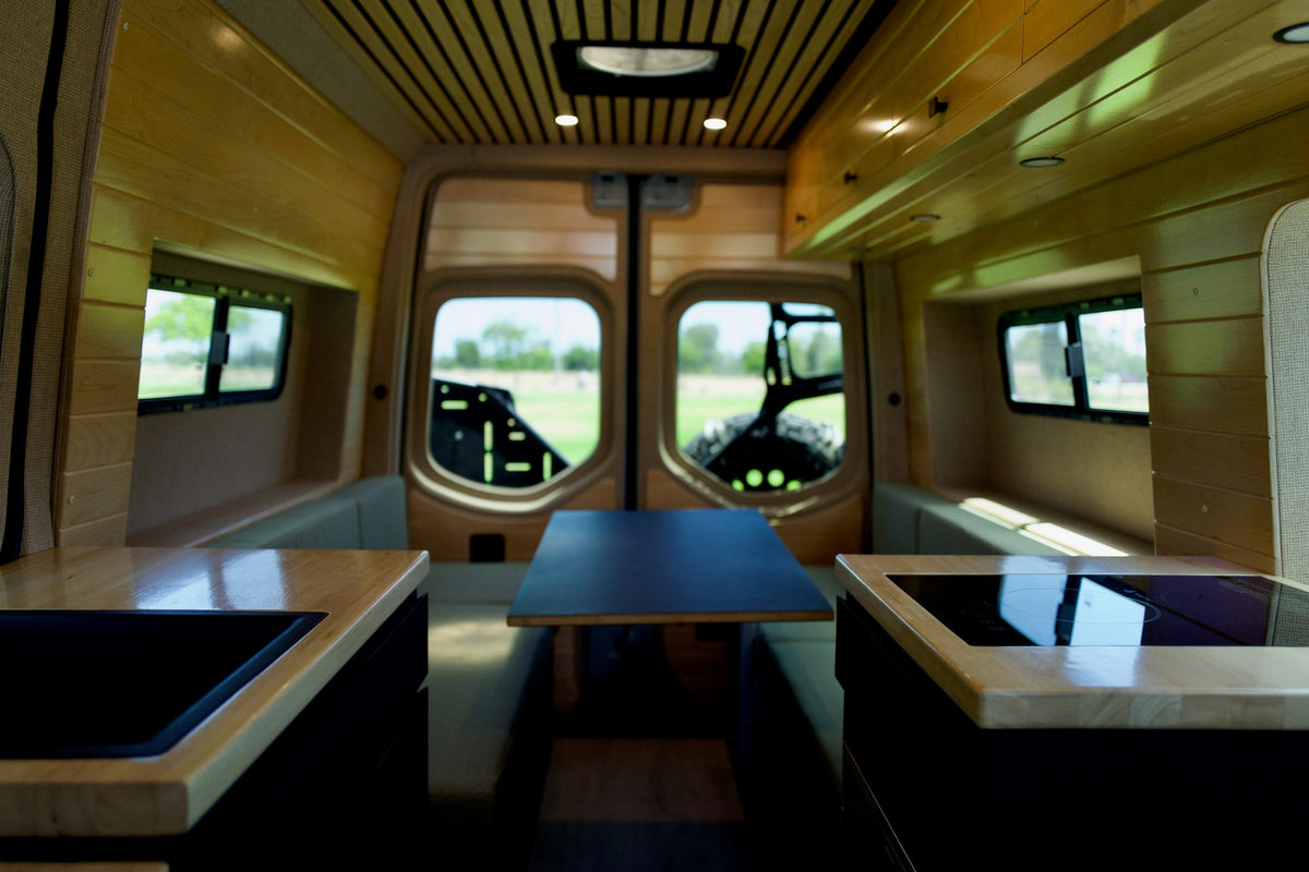 Explore this bright RV rental! Wood-paneled interior features a dining table, kitchen counters with stove & sink. — photo 3