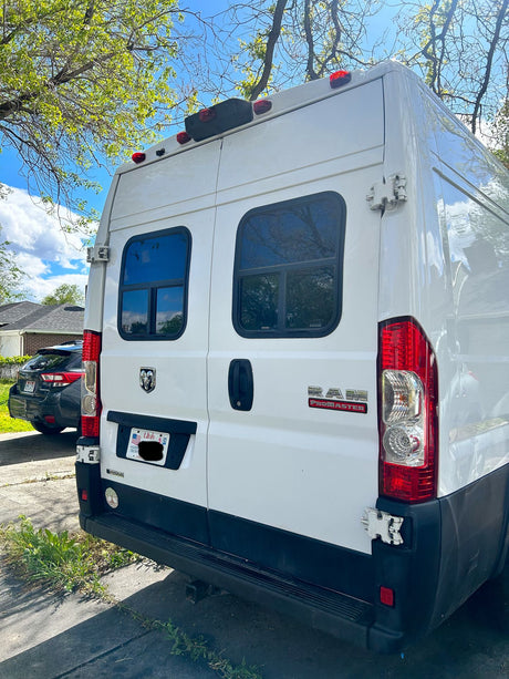 Rear of a white Ram ProMaster cargo van, perfect for an RV rental, parked outdoors on a sunny day.