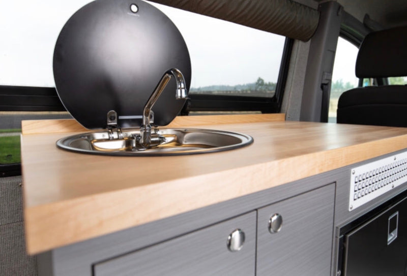Inside an RV rental: a bright kitchenette with a wooden countertop, stainless steel sink, and storage cabinets below. — photo 9
