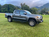 This gray pickup truck parked on lush Hawaiian grass with misty mountains hints at epic journeys, like those with an RV rental.