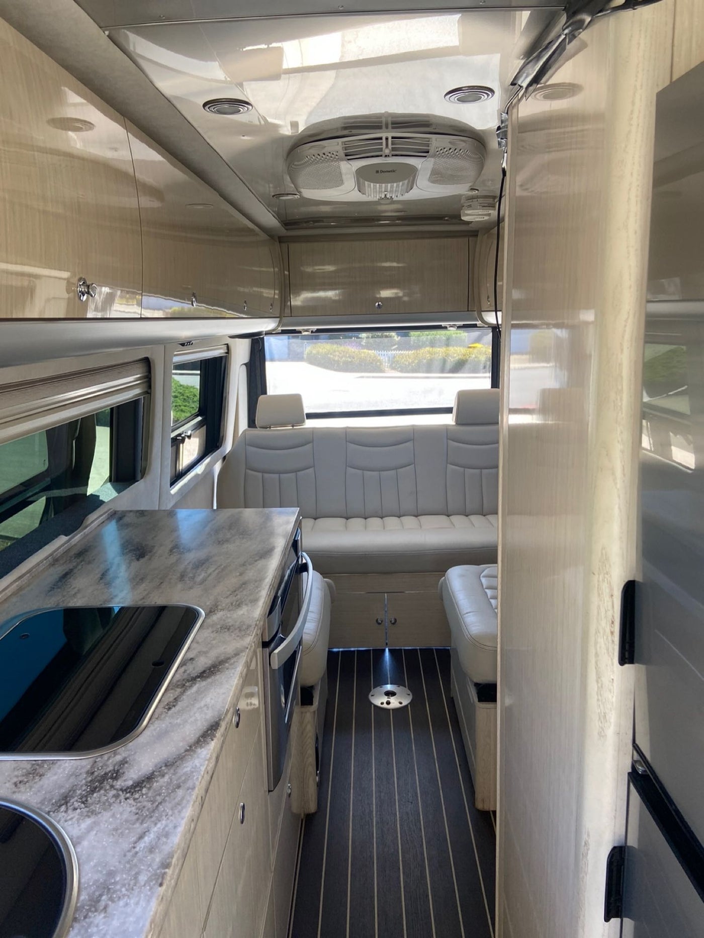  all with safety belts.|Woman stands in an Airstream RV rental with awning extended at a sunny campground. Perfect for your next road trip!|Spacious RV rental interior featuring a modern kitchen — photo 3