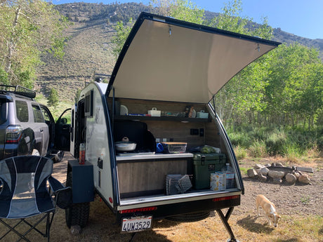 Enjoy a scenic RV rental camping trip! This teardrop camper's open kitchen is ready for adventure in the mountains.