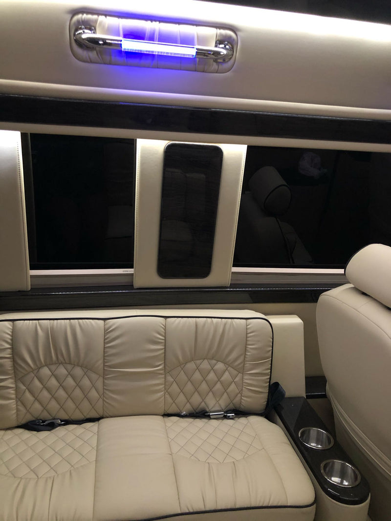 Plush cream leather interior of an RV rental, featuring diamond-stitched seating, cup holders, and overhead blue lighting for comfortable travel. — photo 17