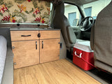 Inside a comfortable RV rental: custom wood cabinetry, sink, bed, and driver's cockpit view. Perfect for travel.