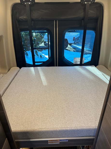 Cozy RV rental interior with a comfy bed at the back.