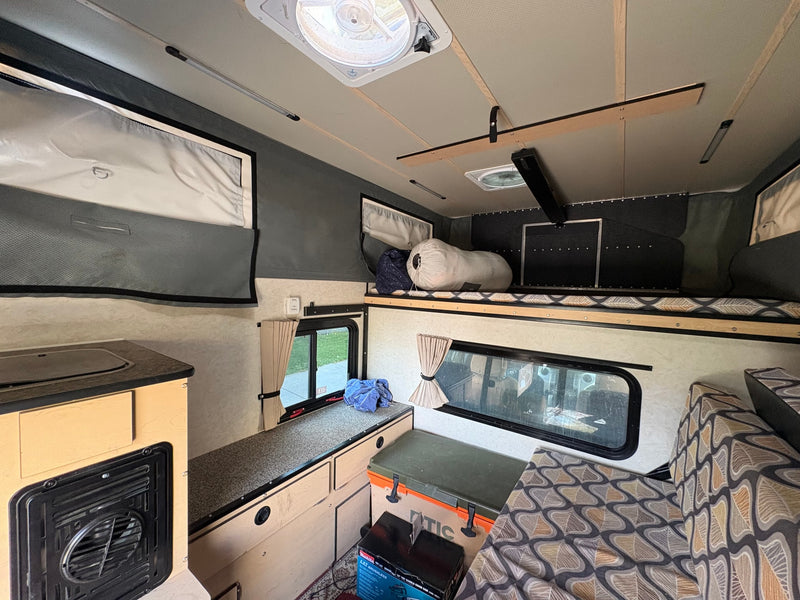 Explore this cozy RV rental interior: kitchenette, sleeping bunk, and comfortable seating for your next adventure. — photo 4