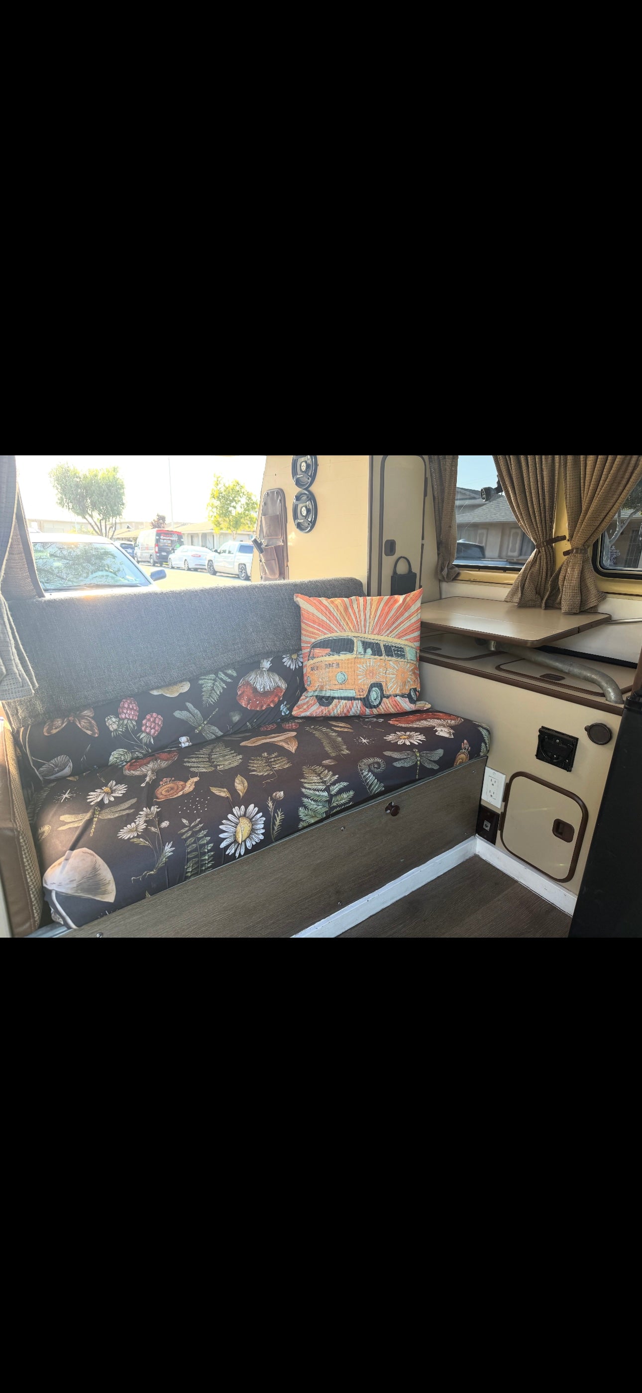 Comfortable RV rental interior: floral bench cushions, a vintage VW van pillow, and a cozy dining area. — photo 2