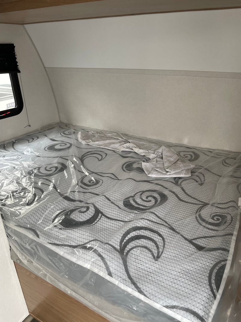 New RV rental bedroom with a gray patterned mattress still in clear plastic wrap, ready for comfortable stays. — photo 6