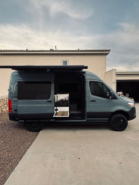 This Storyteller Overland MODE van, perfect for RV rental adventures, has its side door open, revealing a forest design inside.