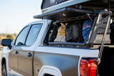 White & grey pickup truck with open bed storage, bags, & a rooftop tent. Ready for your next rv rental adventure!
