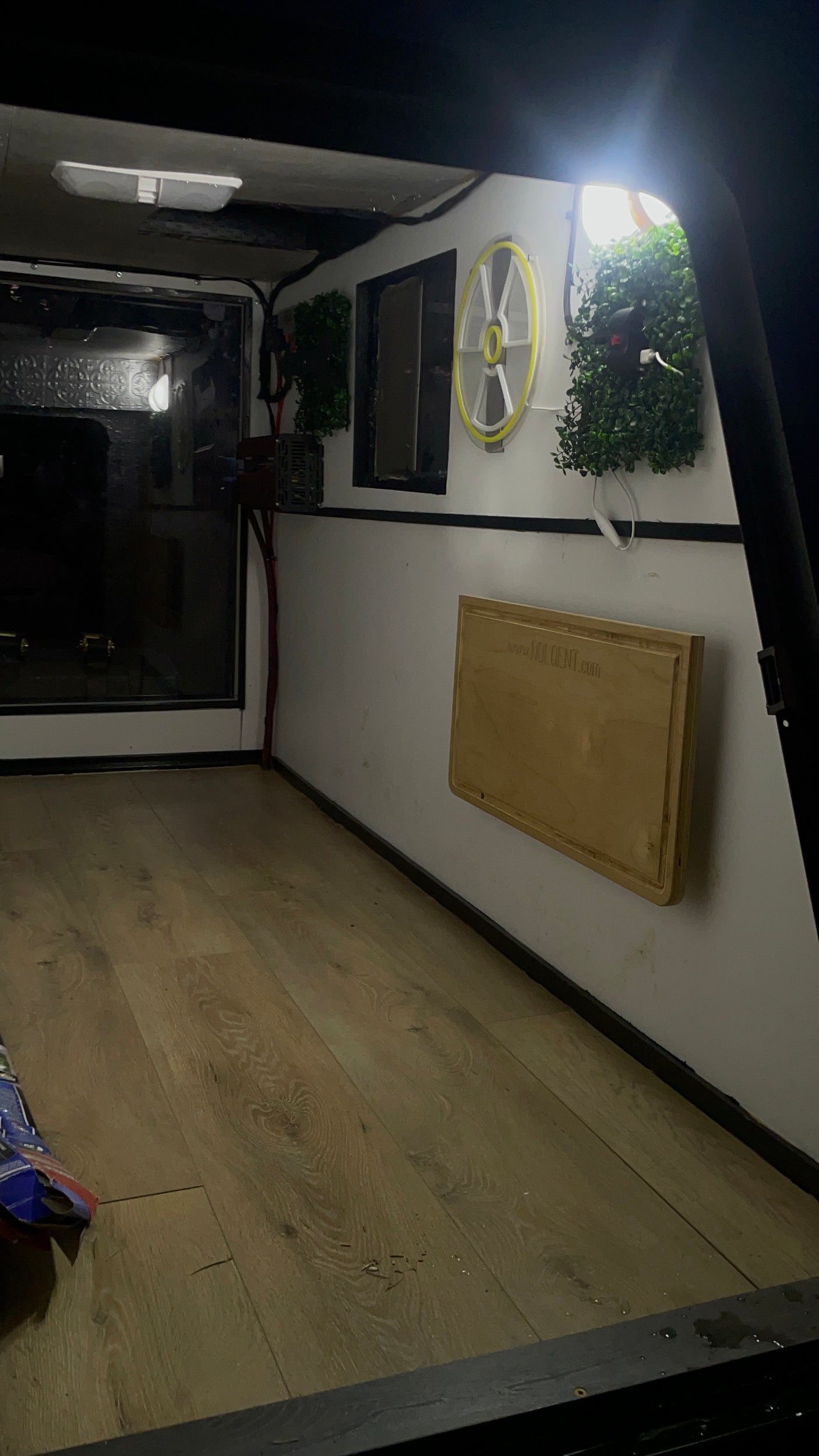 Cozy RV rental interior featuring a wooden floor, wall-mounted fold-down table, and bright lighting, ideal for compact living on the go.