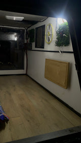 Cozy RV rental interior featuring a wooden floor, wall-mounted fold-down table, and bright lighting, ideal for compact living on the go.