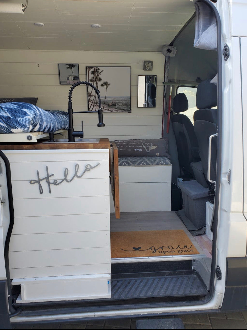 Step into this bright RV rental camper van, featuring a modern kitchen sink, comfy bed, and cozy seating area.