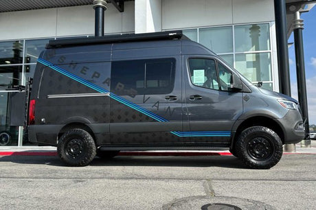A custom gray Shepard Sprinter van, equipped for adventure with off-road tires. Great for an rv rental experience.