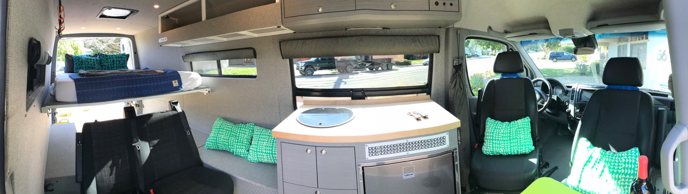 Panoramic view of a modern **rv rental** interior featuring a raised bed, full kitchen setup, and comfortable seating. — photo 7
