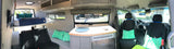 Panoramic view of a modern **rv rental** interior featuring a raised bed, full kitchen setup, and comfortable seating.