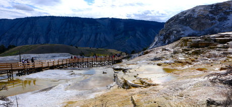 RV rental vacationers explore Yellowstone's stunning Mammoth Hot Springs: mineral terraces, steaming pools, and a scenic boardwalk.