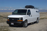 White cargo van with roof rack, ideal for RV rental adventures, parked on a dirt road with snow-capped mountains in the distance.